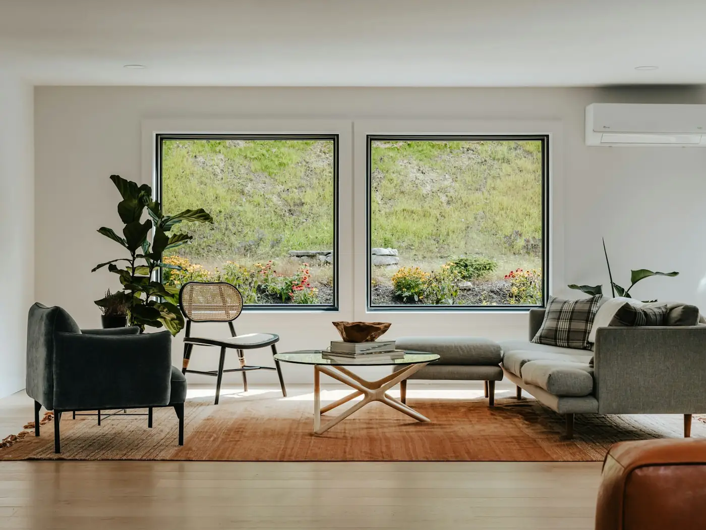 Gepflegtes, helles Wohnzimmer mit Sofa und großen Fenstern